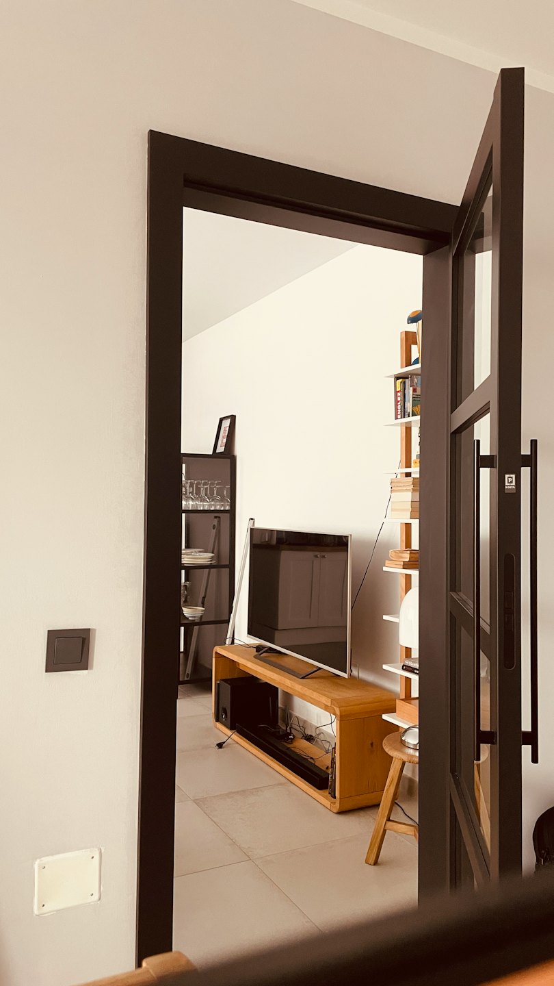 Modernes Wohnzimmer mit Fernseher und Bücherregalen.