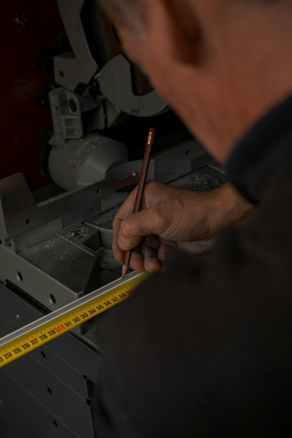 Handwerker markiert Metall mit Bleistift und Maßband in Werkstatt.